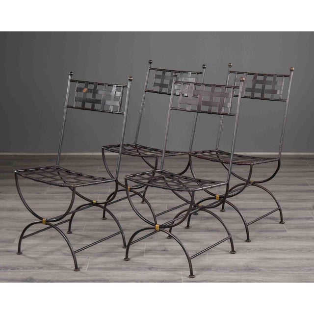This set of four side chairs is constructed in dark-patinated iron in the Curule tradition, each featuring a tall straight...