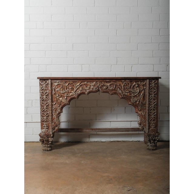 A richly sculpted wooden console defined by its intricate floral relief and strong architectural presence. The piece...