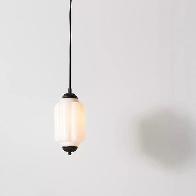 This elegant pendant light from Anthropologie features a white glass shade with a vintage-inspired design and stylish dark...