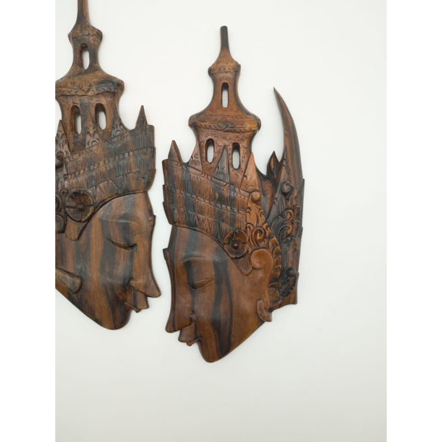 An elegant pair of Balinese wall masks/reliefs from the mid-20th century (circa 1960s). Masterfully handcrafted from...