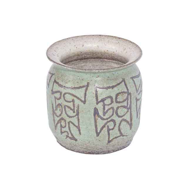 A 1972 studio pottery vase. This vase features a green glaze with puzzle piece style designs on the exterior. The...