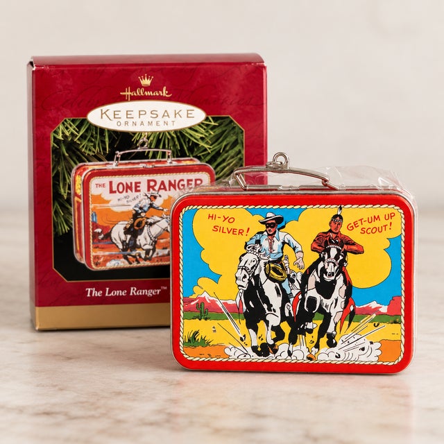 A nostalgic 1997 Hallmark Keepsake Christmas ornament depicting a miniature vintage-style Lone Ranger lunchbox, designed...