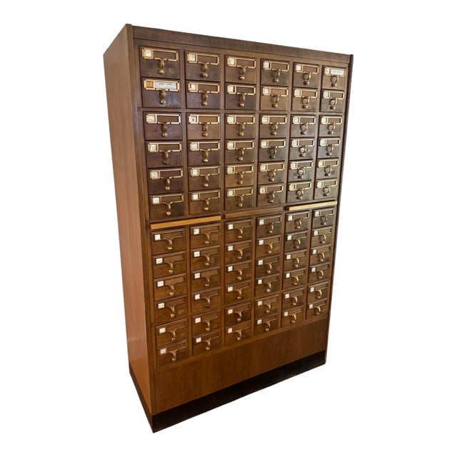 A substantial vintage library card catalog featuring 72 wooden drawers, brass-toned label holders and pulls, and two...