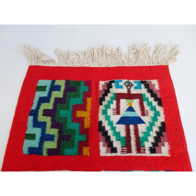 This hand-woven rug is a Tunisian wall hanging from the 1960s. The wall rug has a narrow long shape with fringes and a...