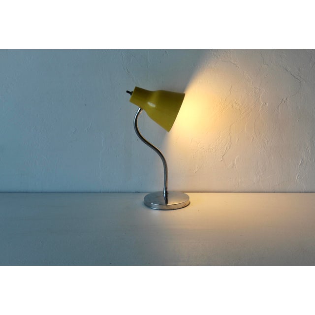 A vintage yellow metal gooseneck desk lamp with Mid-Century Modern or 1970s design. Retro industrial chic with a yellow...