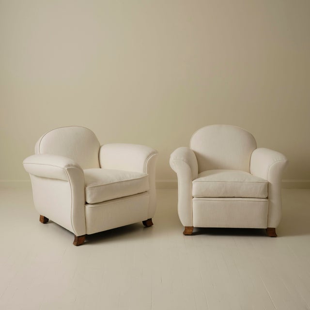 Pair of French Art Deco club chairs, with plush barrel backs and generously rolled armrests. The chairs rest on low,...