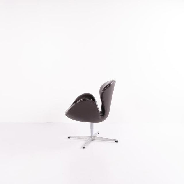 Swan chair designed by Arne Jacobsen and produced by Fritz Hansen in 2002. Upholstered in Dark Brown leather, with a depth...