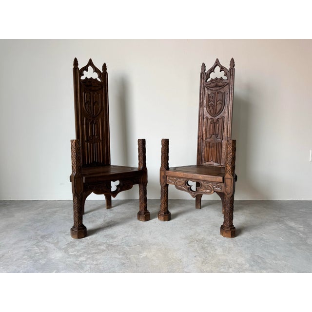 Magnificent pair of antique Spanish Gothic Revival-style throne chairs, finely hand-carved from solid wood. Each chair...