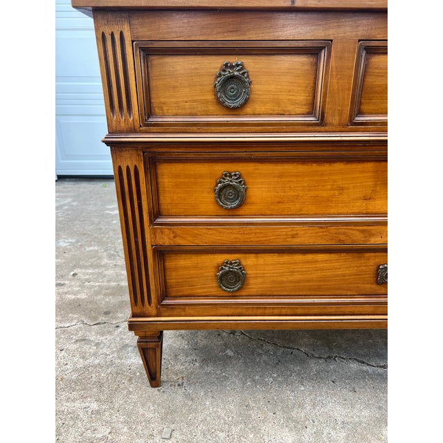 Elegant French 19th-century Louis XVI walnut commode featuring three drawers, paneled fronts, carved fluted sides,...