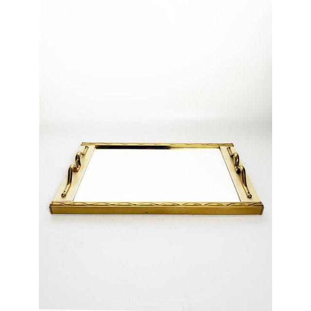 Elegant French serving tray dating from the 1960s, featuring a rectangular mirrored surface framed in gilt metal. The...