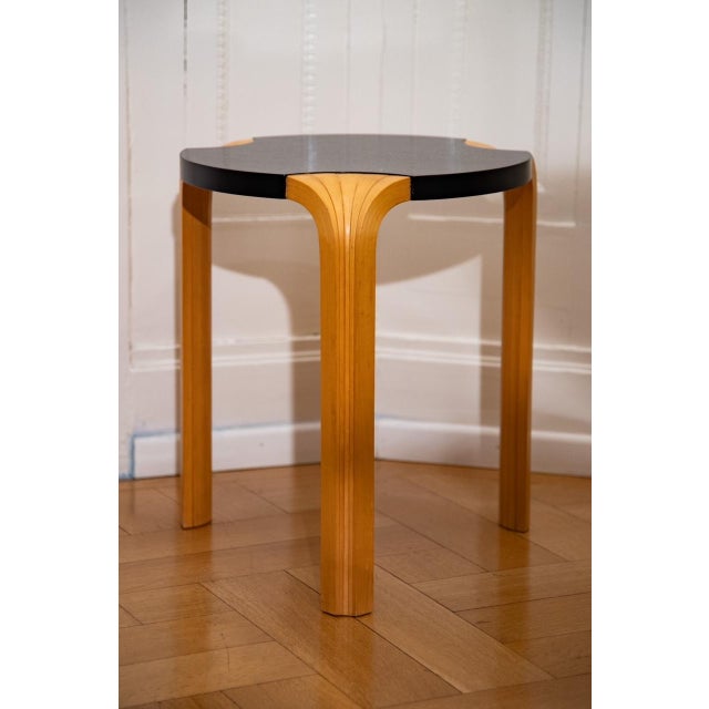 The unusual, iconic fan leg stool 'X600' by Alvar Aalto has a black lacquered seat and is stamped on the underside. It...