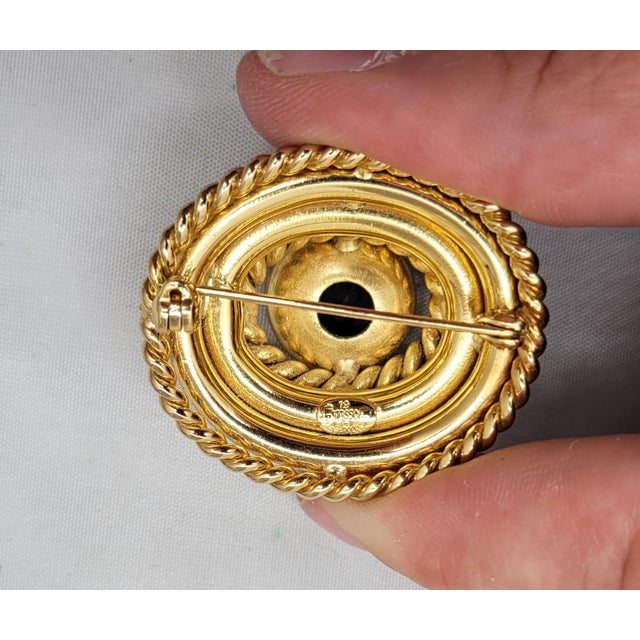 Goldtone oval domed round center with "rope" surround with two smooth "tiers" below it and a final "rope" surround on the...