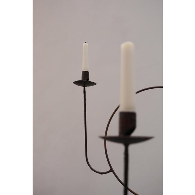 A pair of standing metal candelabras, each built around an open circle that holds two candles. They have something sacred...