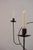 A pair of standing metal candelabras, each built around an open circle that holds two candles. They have something sacred...