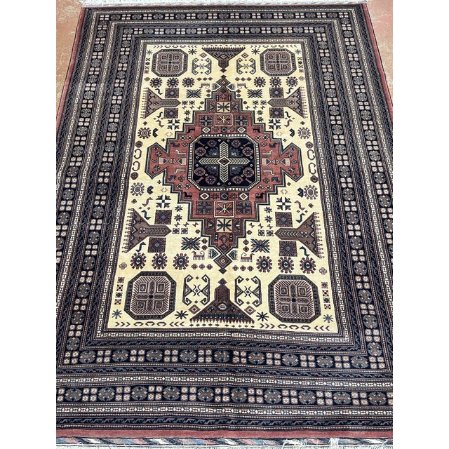 Afghan Turkmen geometric design rug, hand-knotted in Afghanistan from 100% wool. Measuring 6’8” x 9’10”, the rug features...