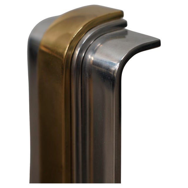 A striking pair of Art Deco style polished steel and brass andirons, designed by Danny Alessandro and sold through Holly...
