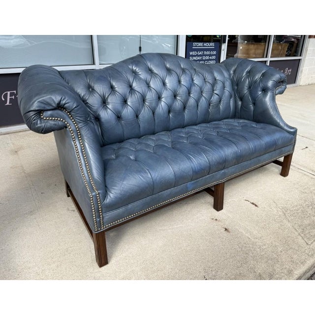 This Vintage Blue Leather Camelback Chesterfield Sofa features rich blue leather upholstery with deep button tufting...