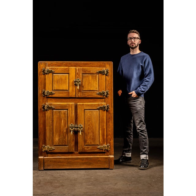 Antique wooden ice box with original brass hardware. This piece features cabinet-style doors that latch in place to...