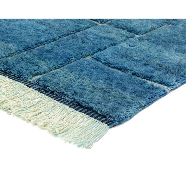 The blue city, rendered in wool — deep, luminous, and quietly geometric. This hand-knotted wool rug immerses the eye in a...