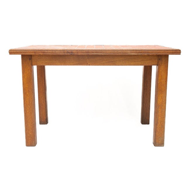 Kitchen table in solid oak. Ceramic tile top. Multiple shades of orange. Sturdy and stable. Circa 1950