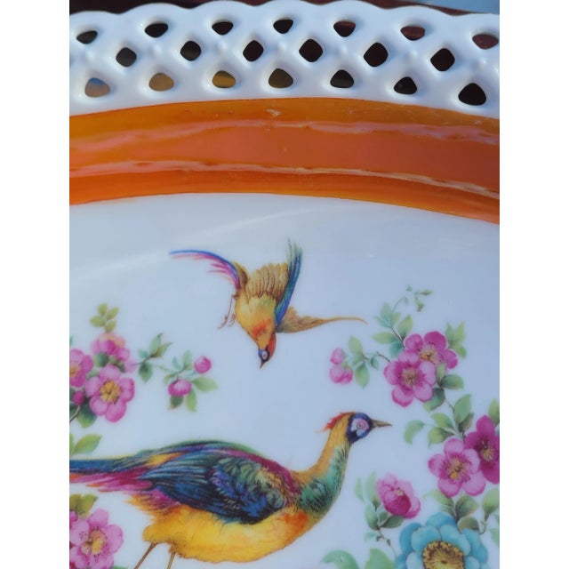 Here is an oval shaped reticulated bowl with scalloped border of gold gilt. A center floral and bird motif is framed in a...