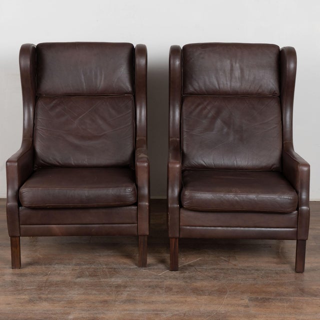 Pair, mid-century modern wingback arm chairs from Denmark. Vintage dark brown leather with loose seat and back zipper...