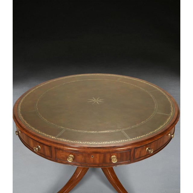 A smart regency mahogany fixed top drum table, the crossbanded edge with and intricately embossed inset green leather top,...
