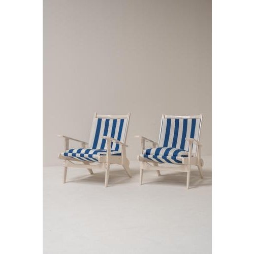Striking pair of wooden lounge chairs in classic French Riviera style, newly upholstered with bold blue-and-white striped...