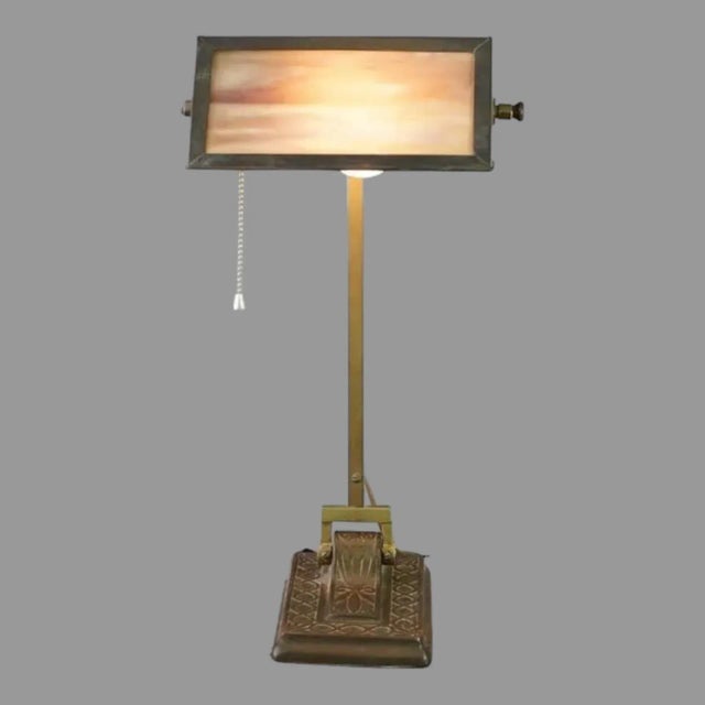 An antique Arts and Crafts brass bankers desk lamp in the style of Bradley & Hubbard with adjustable shade having slag...