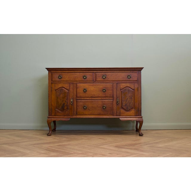 An early 20th century walnut sideboard, raised on elegant Queen Anne style cabriole legs and featuring figured burr walnut...