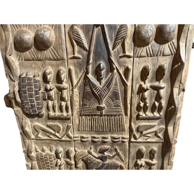 This vintage Dogon granary door from Mali features intricate carved relief figures—standing Nommo ancestors on the top and...