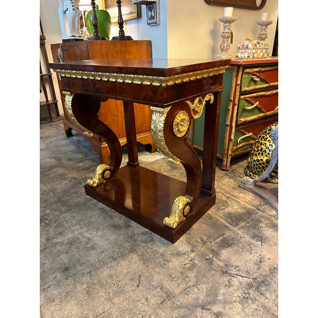Impressive 19th century English console handcrafted in mahogany in an elegant empire form with carved and guilt highlights.