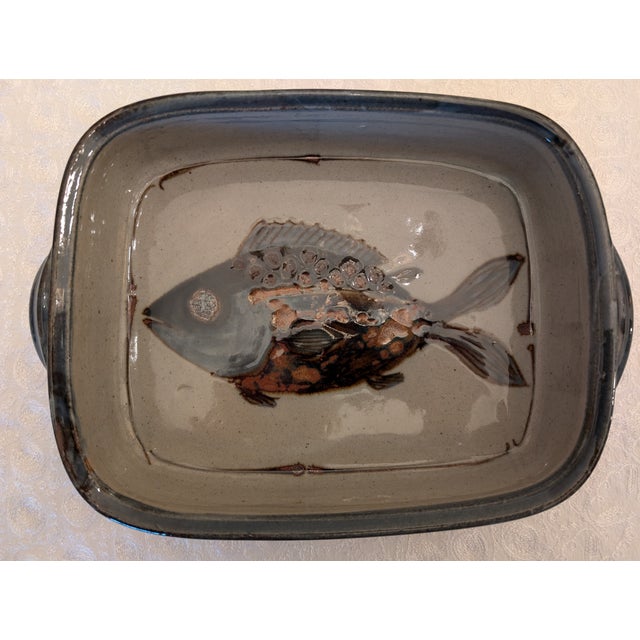 A hand-crafted rectangular pottery serving dish with a colorful fish design in rich blues and tans. Made in South Africa....