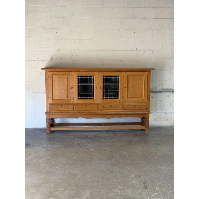 This large sideboard by Henning Kjærnulf features four upper cabinet doors including central leaded glass panels and four...