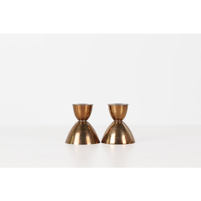 Pair of vintage copper taper candleholders in a sculptural hourglass silhouette, with a rounded cup rising from a wide...