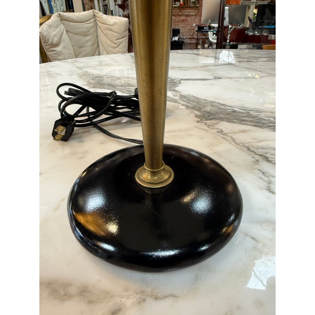 Elegant vintage Mid-Century Modern table lamp featuring a sleek black metal dome shade, tapered brass stem, and matching...