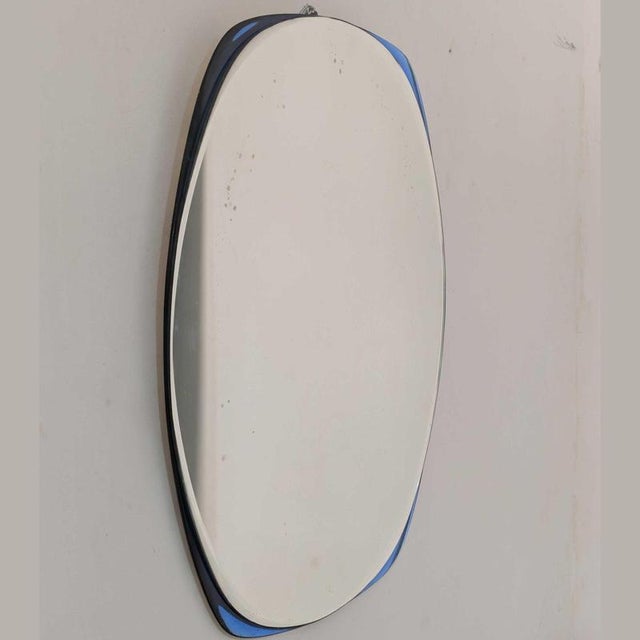 An elegant 1970s Italian Cristal Art mirror, featuring a cobalt blue curved glass frame and a beveled centerpiece. The...