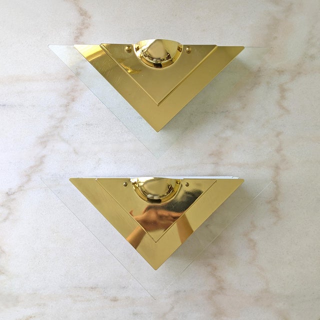 A pair of vintage electric wall sconces featuring Art deco style lucite and brass design.