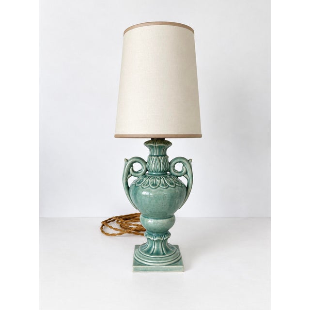 Small ceramic table lamp in with urn shaped body and scrolled handles with acanthus leaf details in celadon glaze. Lamp...