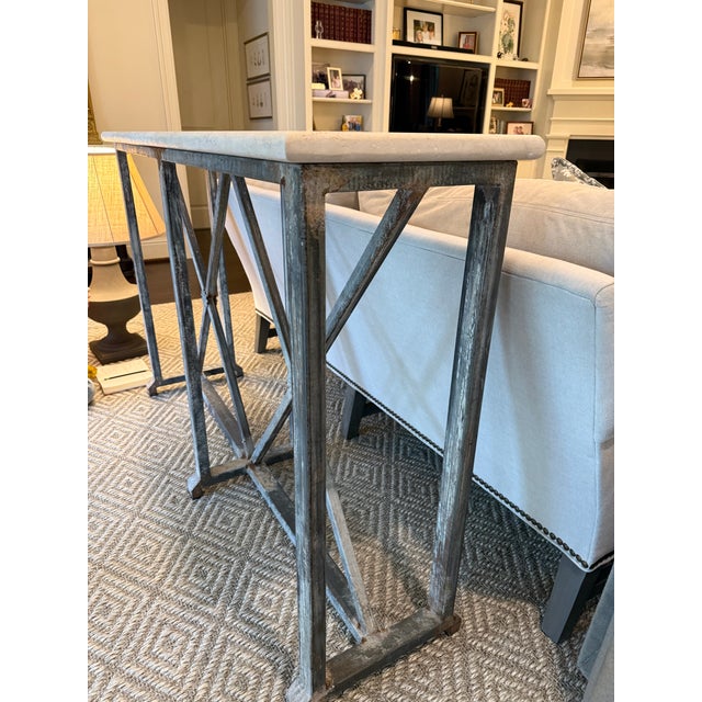 Limewashed iron console table with white stone top. Iron base features floral medallions on the intersecting legs. Good...