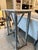 Limewashed iron console table with white stone top. Iron base features floral medallions on the intersecting legs. Good...