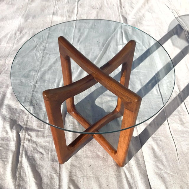 An iconic MCM design, this round glass top table with sculpted "ribbon" wood base is in the manner of Adrian Pearsall....