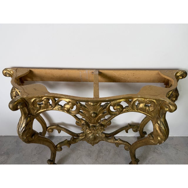 A stunning vintage Hollywood Regency style console table base featuring elaborate carved wood details with a rich gilt...