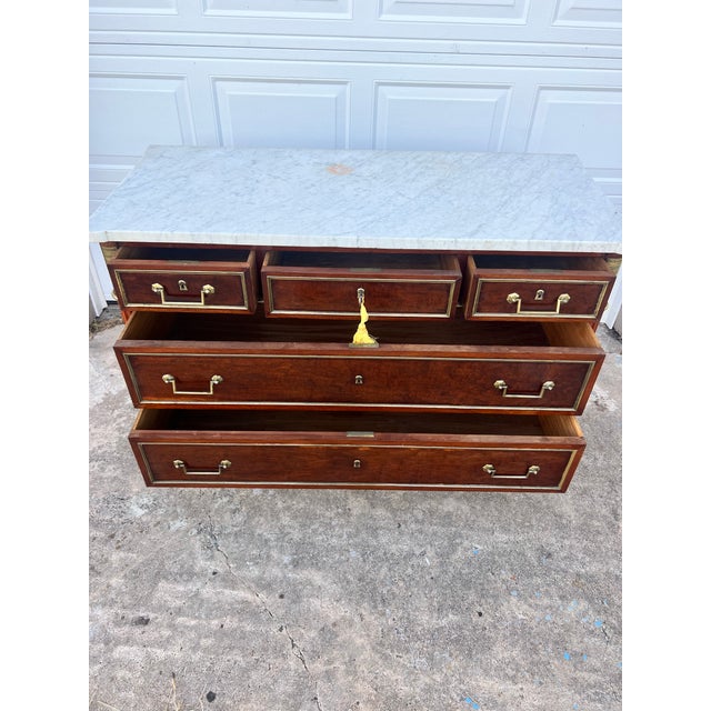 Elegant 19th-century Louis XVI style commode featuring a beautifully figured mahogany veneer with a white marble top. The...
