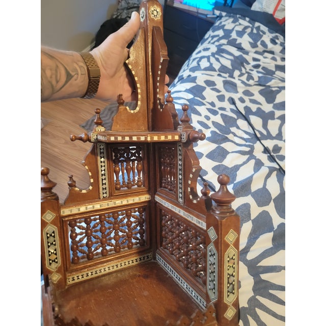 This is a Syrian style corner shelf featuring intricate mother of pearl inlay and detailed wood carving.
