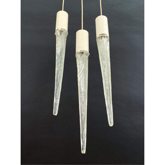 A set of three unique acrylic and metal icicle-form Danish pendant lights by Fog and Morup. Light bulbs are held in...