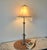 Elegant table lamp featuring a silver metallic finish paired with a soft beige bell-shaped fabric shade with decorative...