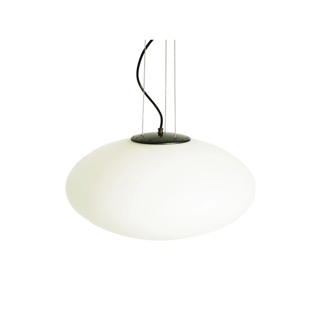 This italian pendant lamp was produced around the 1960s in the style of Stilnovo. It is made from a white oval glass...
