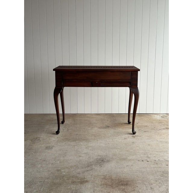 This early 20th century mahogany lift-top writing desk combines the compact footprint of a narrow console with a...