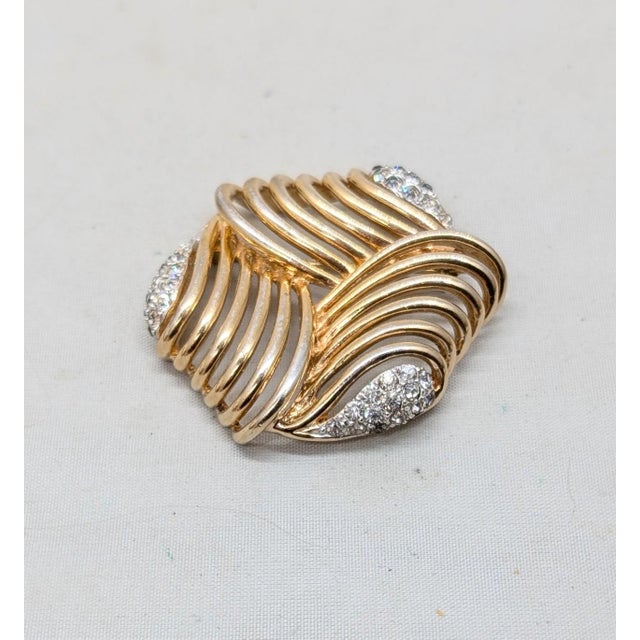 Goldtone openwork with three sections of round clear pavé rhinestones brooch with security clasp. Marked with Boucher's...